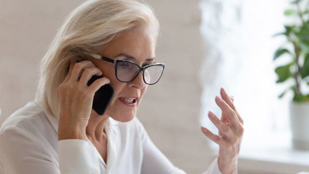 angry older woman on the phone; how to file a complaint against a debt collection agency