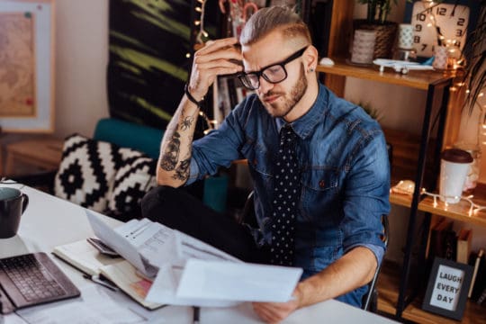 Millennials and money: Young business man covered with papers