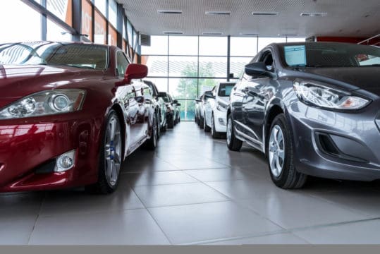 New cars lined up on an auto dealership showroom floor, waiting for car buying financed through auto loans