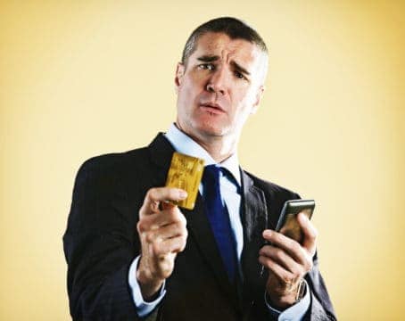 Man holding out credit card questioning how he can pay off his debt without cash.