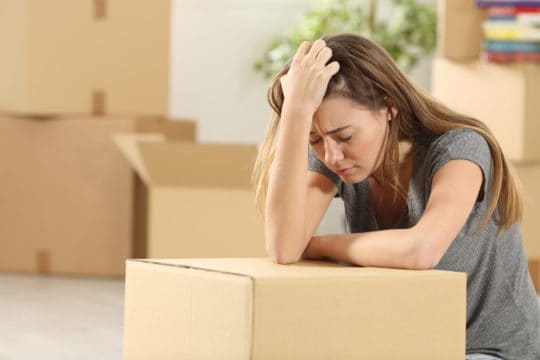 A sad woman packing up her condo because she may be forced to move out