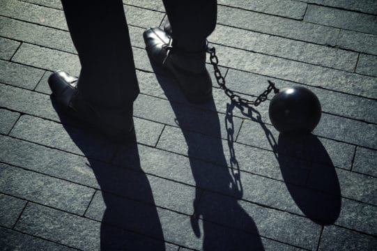 Working man in a suit is chained to his job