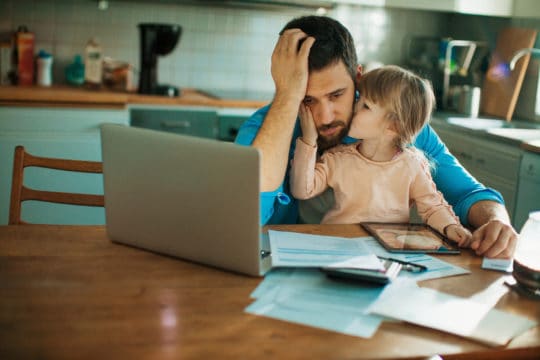 Father and daughter sitting in the kitchen,daughter is comforting her father who is worried about bills