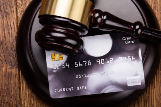 Credit card on wooden gavel at wooden desk in courtroom.