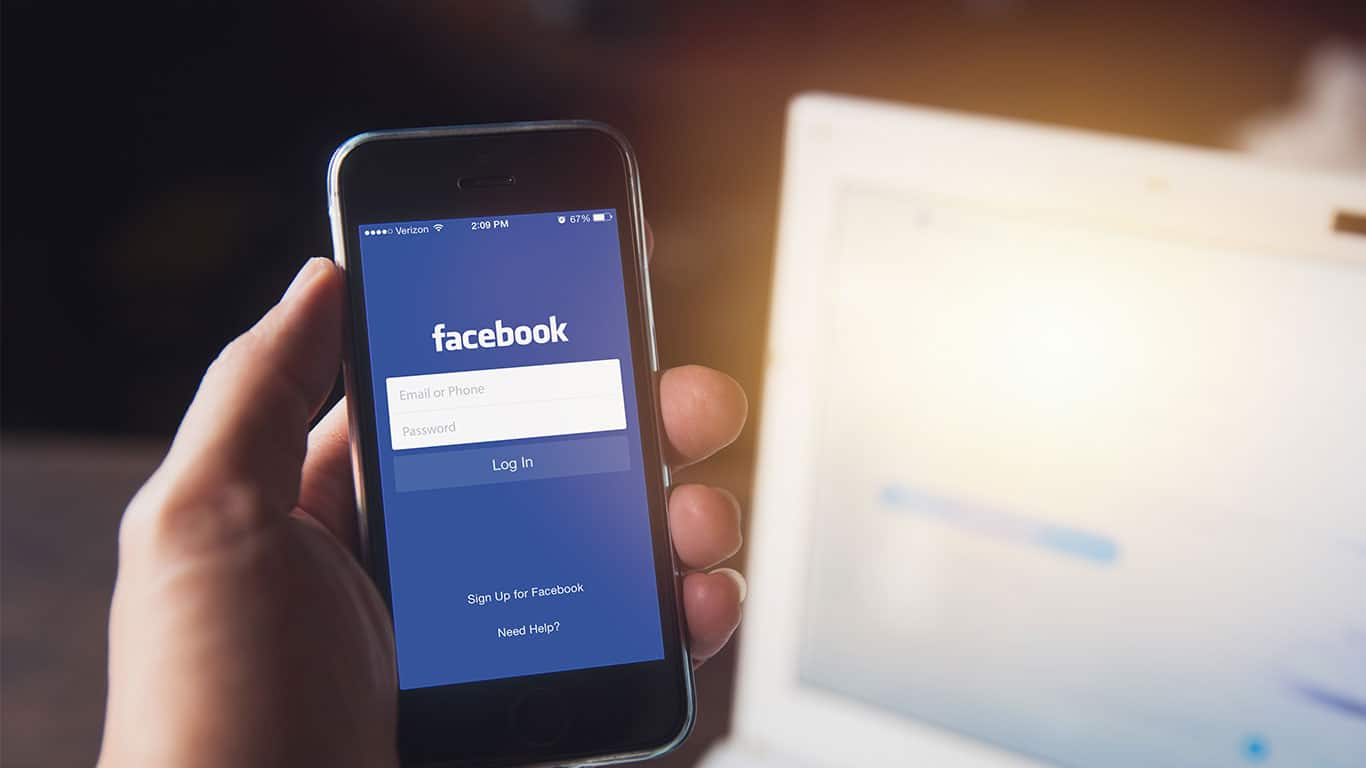 Facebook App on iPhone with computer laptop background
