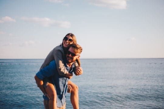 Modern couple on the beach hugging and loving each other prepared for retirement