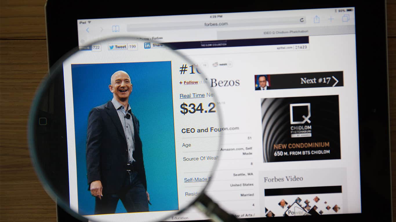 Jeff Bezos on a ipad monitor screen through a magnifying glass