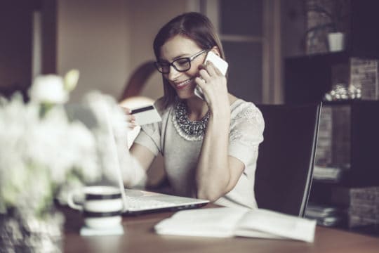 Young woman on phone with credit card company; how often is your credit score updated