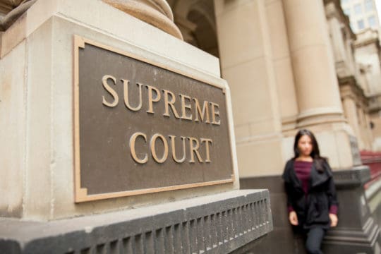 A woman waits outside the Supreme Court building