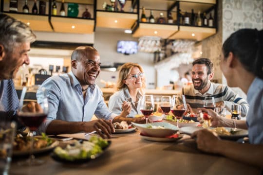 Cheerful business colleagues talking about something funny on a lunch break in a restaurant.