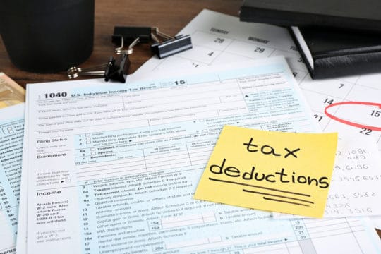 Paper sheet with text tax deductions and individual tax return form on table