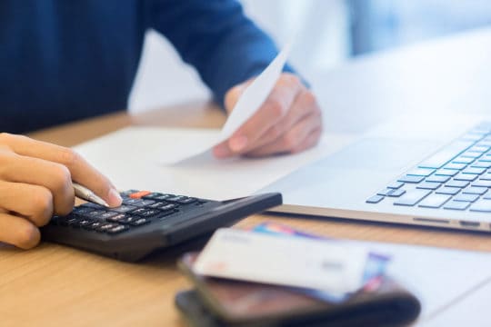How to deal with shady collection agencies: man writing on notebook and calculating on calculator