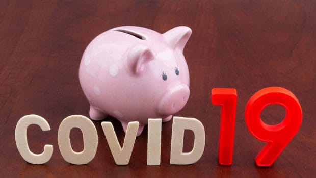 Save money in coronavirus covid-19 time concept. Piggy bank and word covid19 close up.
