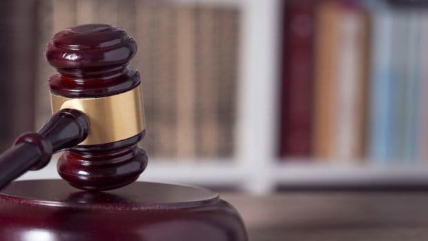 Close up of a judge gavel and law books in the background of a courtroom