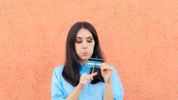 Woman Cutting Credit Card in Half with Scissors