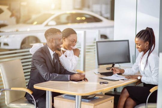 African American couple sitting down and signing an auto loan with their dealer at the dealership