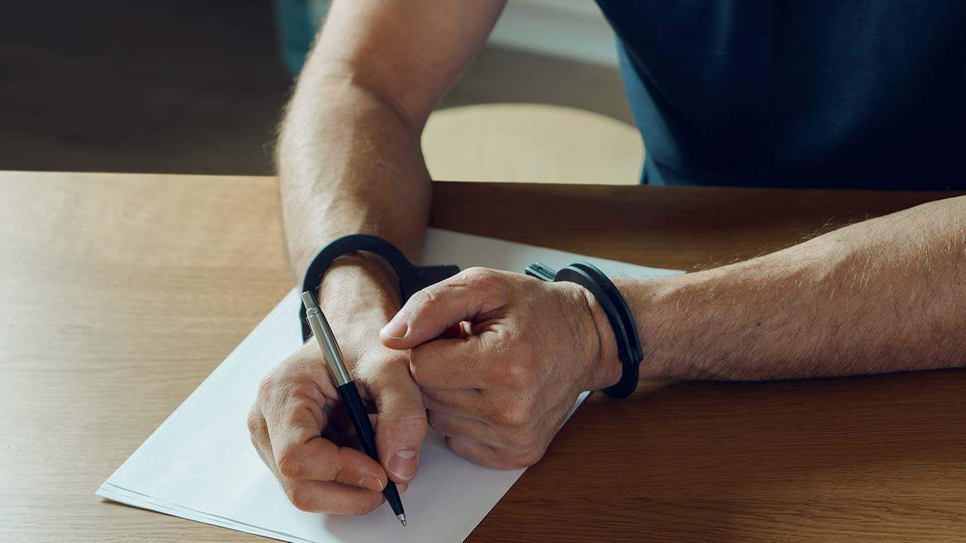 Men hands with handcuffs fill the police record, confession.