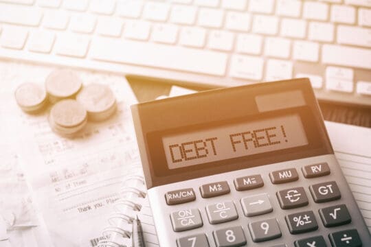 Image of calculator on a desk showing the words "debt-free"