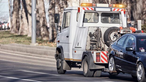 Tow truck carrying improperly parked car or repossessed vehicle