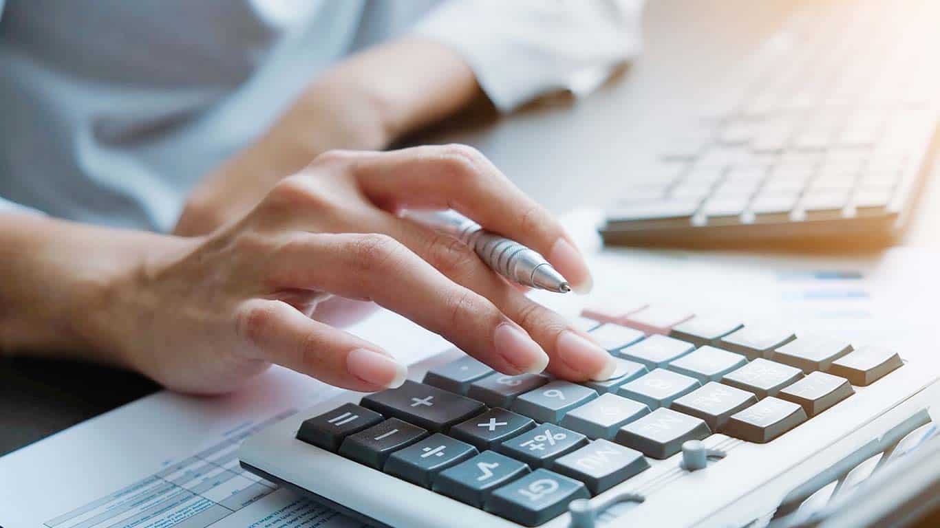 The hand of a woman using a personal loan calculator.