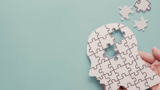 Hands holding brain with puzzle paper