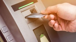 Hand of a man with a credit card, using an ATM