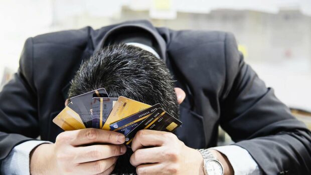Businessman holding credit cards thinking seriously about payment loan problem