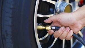 Driver checking air pressure and filling air in the tires close up