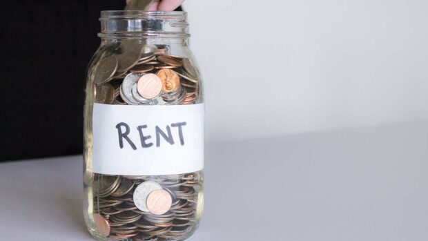 Hand Dropping Change in Rent Jar