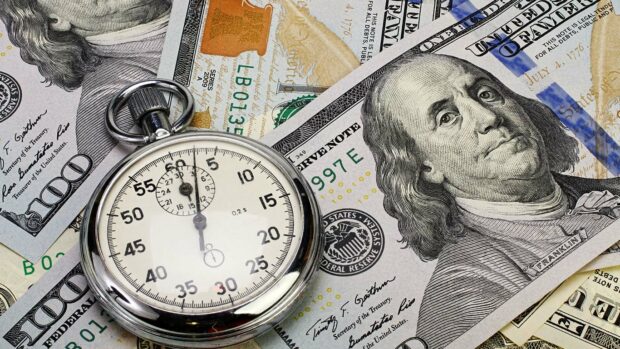 Stopwatch lays on hundred dollar bills.