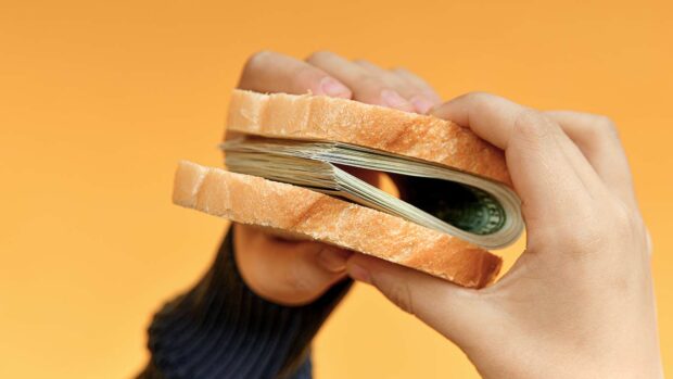 A man holds a sandwich made of money in his hands. Income, success and stability concept.