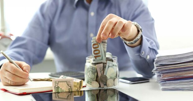 Male hand depositing some extra money in future needs closeup